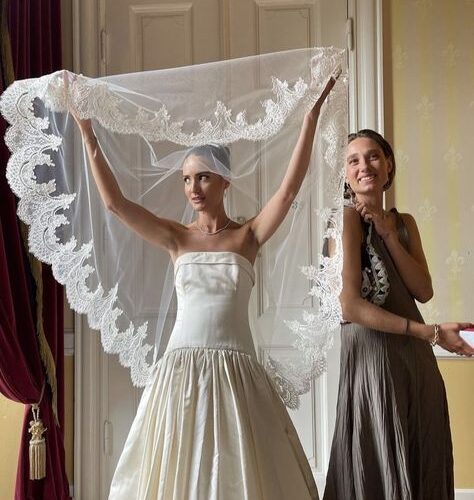Women in wedding dress holding up her veil.