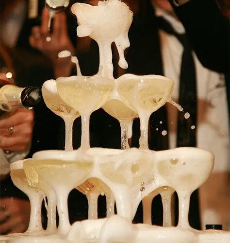 Tower of champagne glasses with champagne being poured onto it